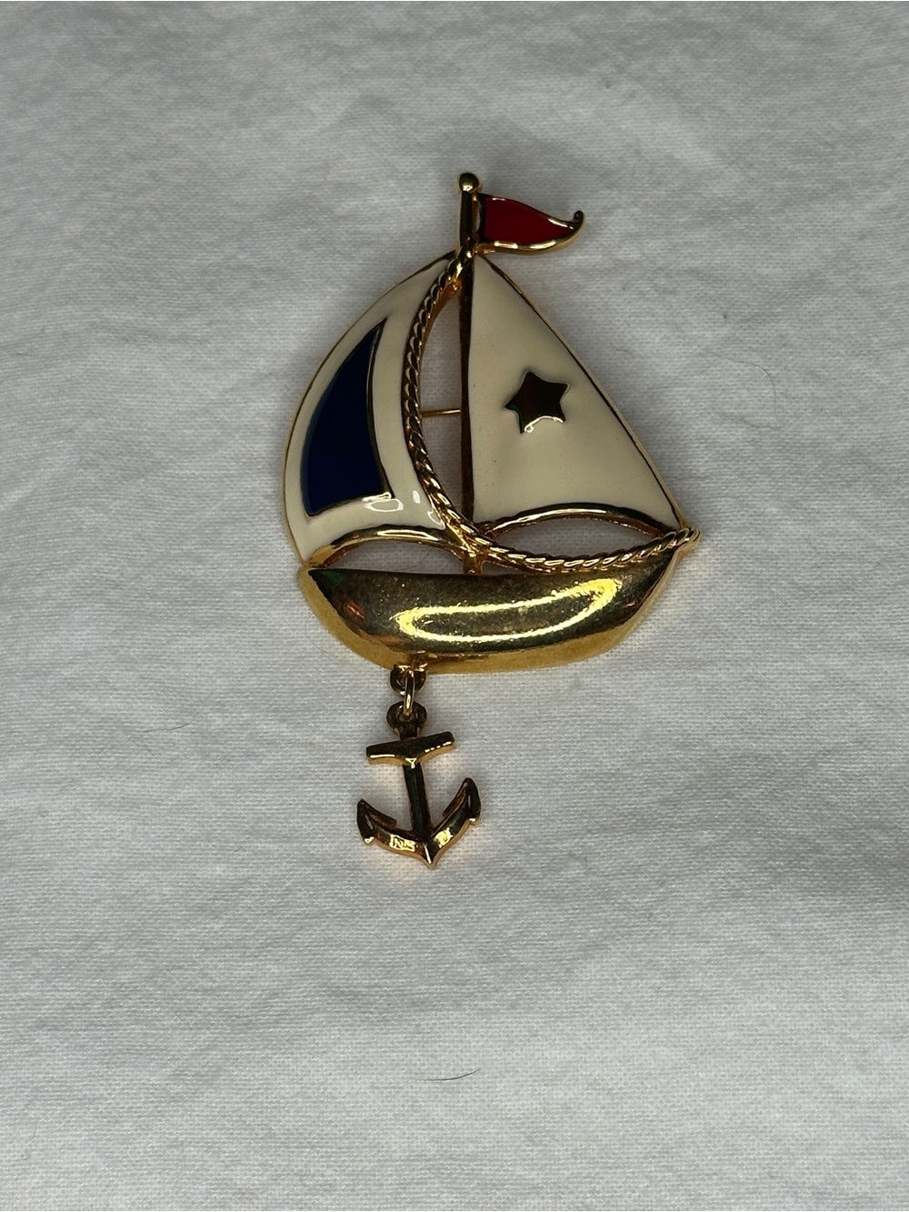Avon gold-tone nautical sailboat brooch featuring white and blue enamel sails.